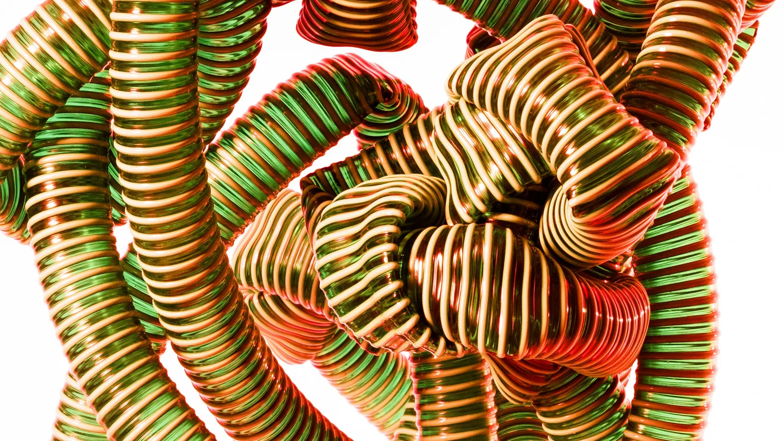 Tangled knot of ribbed green and copper flexible tubes against a white background, a metaphor for complex connections